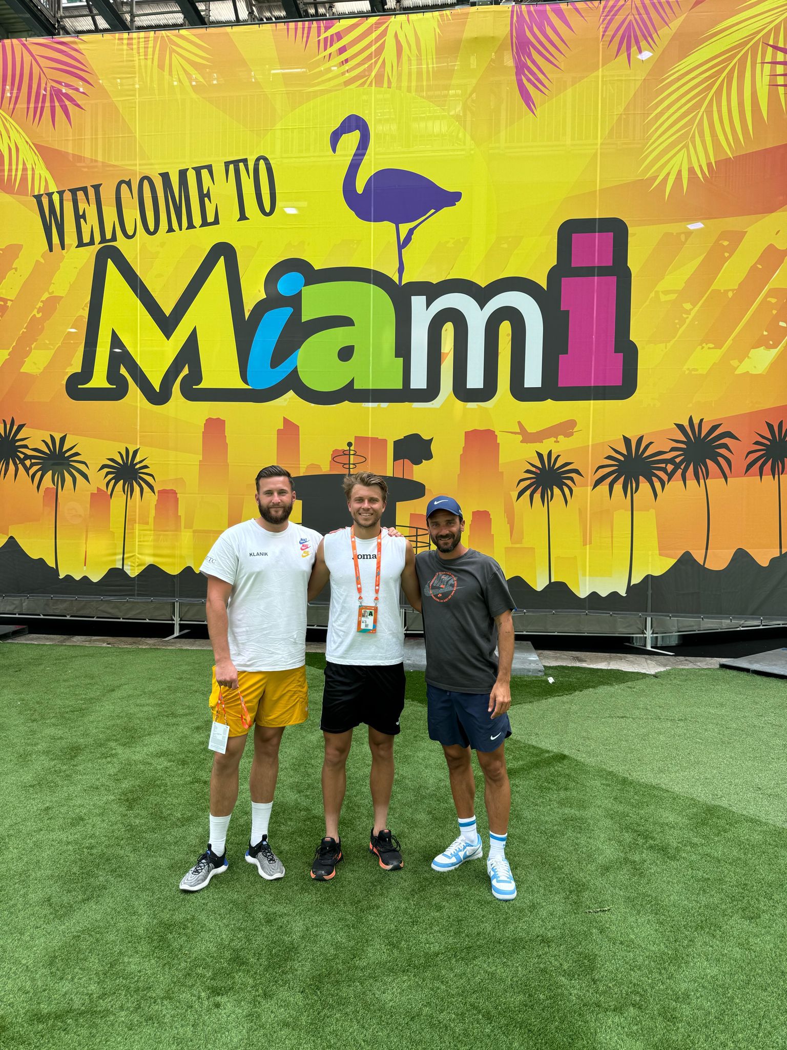 Alexandre Muller, et deux coachs posent devant le panneau 'Welcome to Miami'